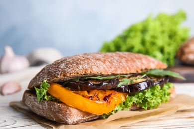 Delicious eggplant sandwich on white wooden table, closeup