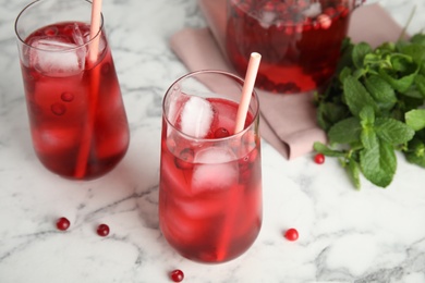 Photo of Tasty refreshing cranberry cocktails on white marble table