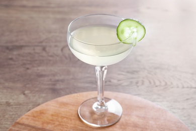 Photo of Glass of tasty cucumber martini on wooden table