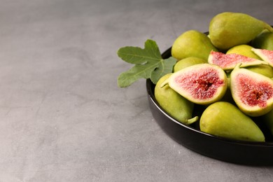 Cut and whole green figs on light gray table, closeup. Space for text