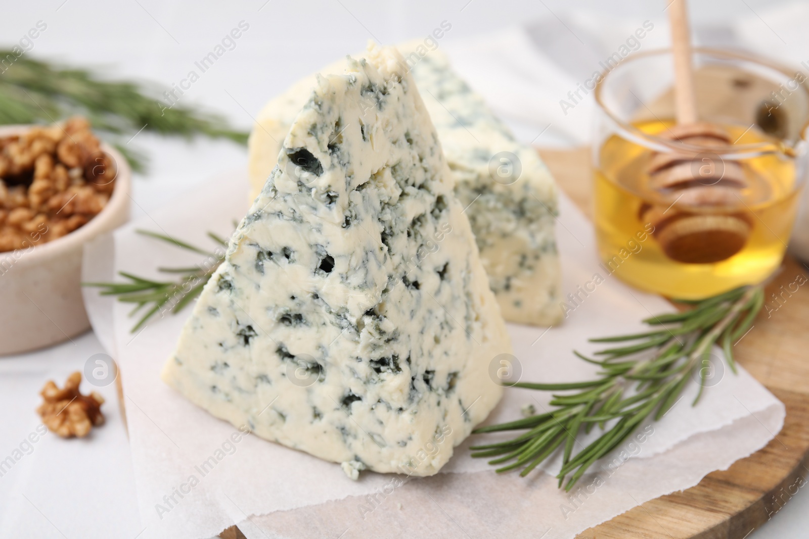 Photo of Tasty blue cheese with rosemary, honey and walnuts on white table, closeup