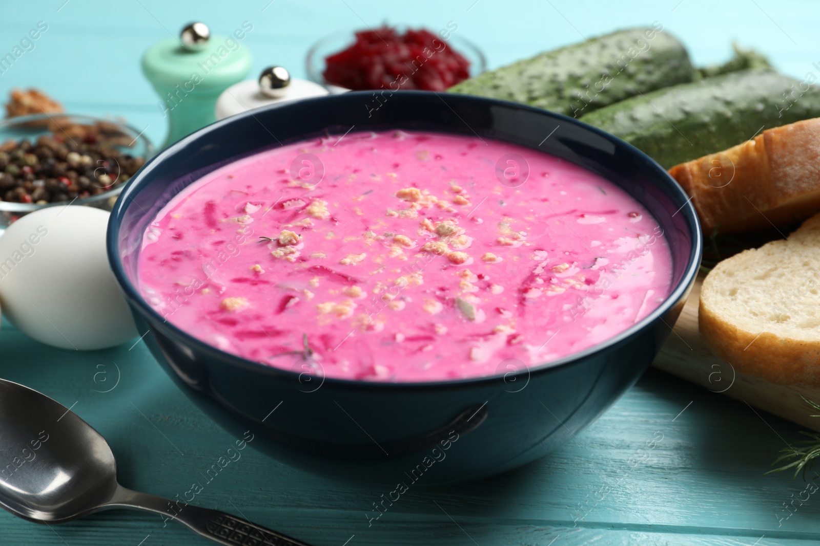 Photo of Delicious cold summer beet soup on light blue wooden table, closeup