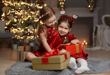 Cute little children with Christmas gifts in living room