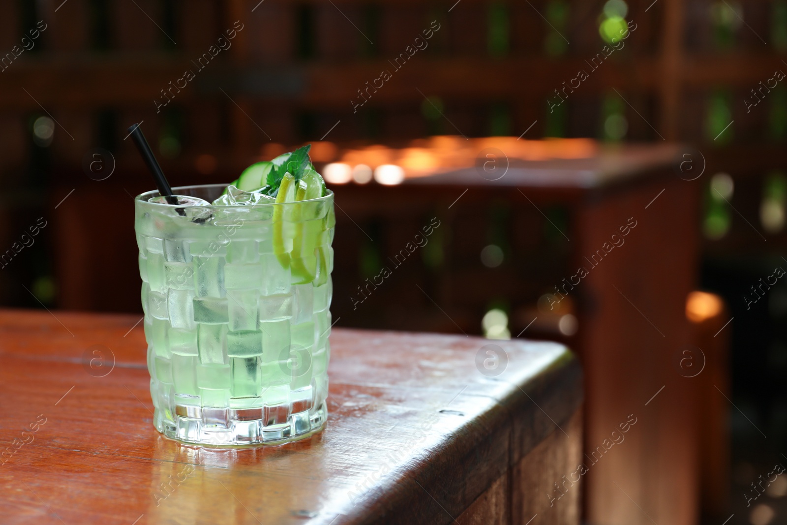 Photo of Glass of delicious cocktail with ice on table in bar