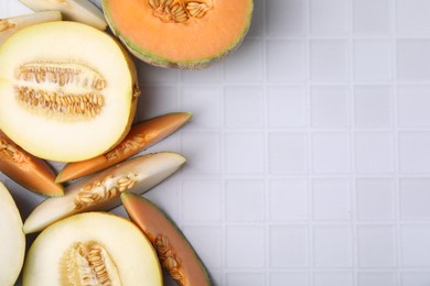 Photo of Tasty colorful ripe melons on white checkered table, flat lay. Space for text