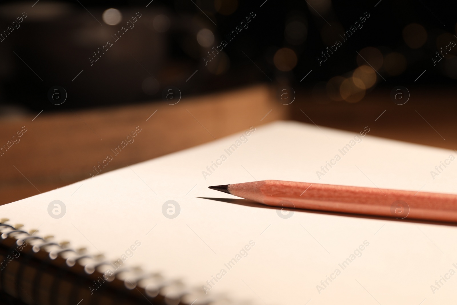 Photo of Blank notebook and pencil on wooden table, closeup