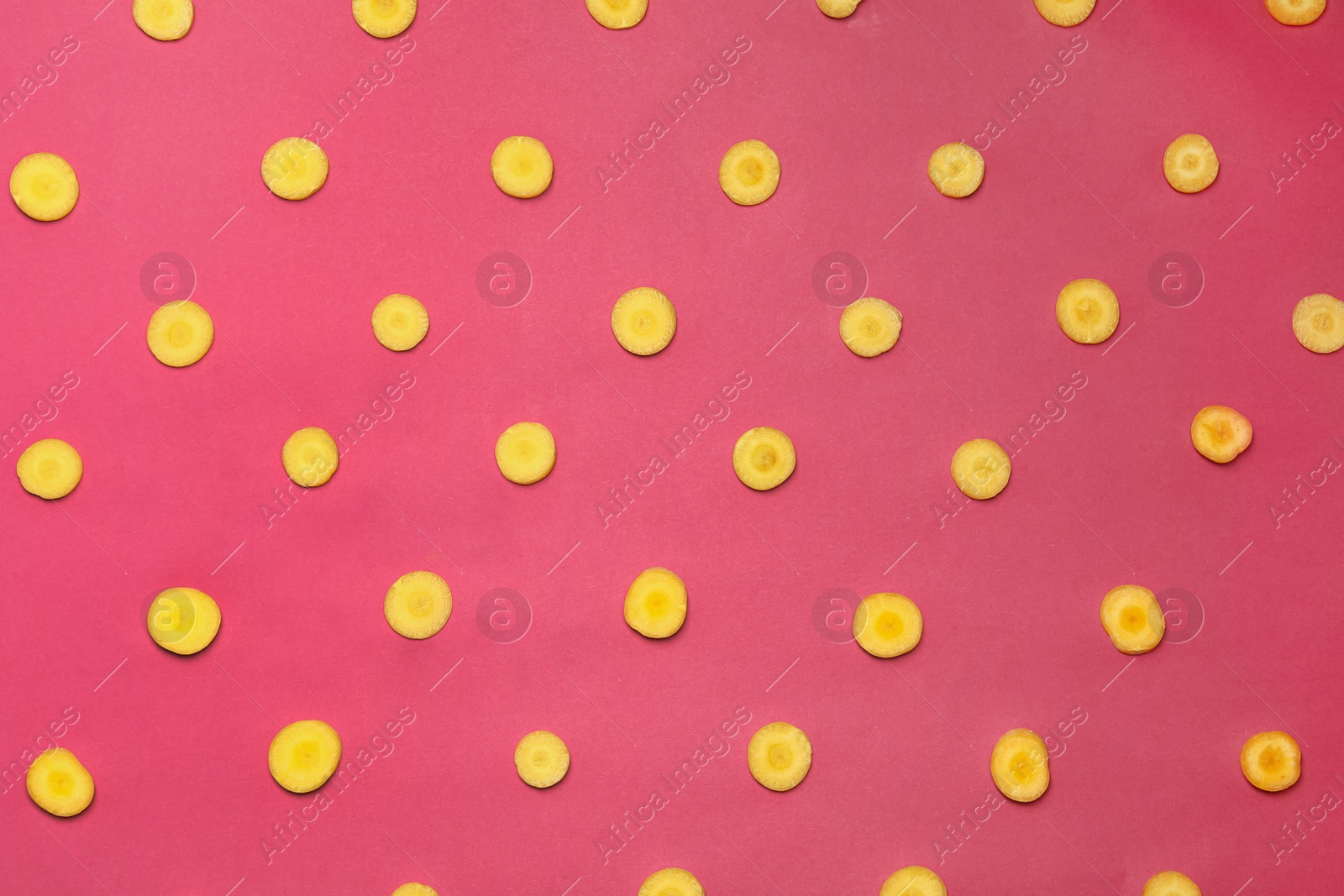 Photo of Slices of raw yellow carrot on pink background, flat lay