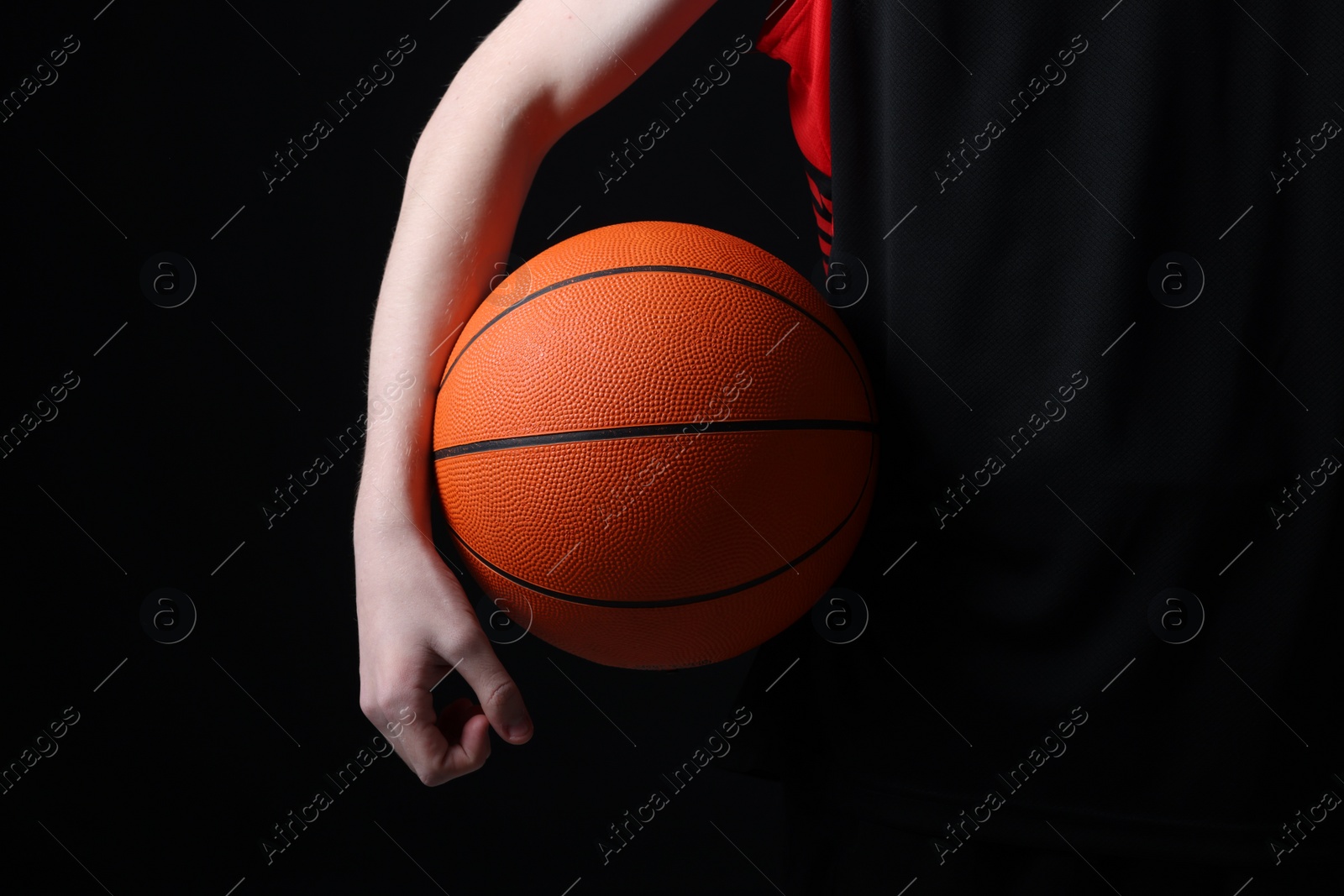 Photo of Boy with basketball ball on black background, closeup