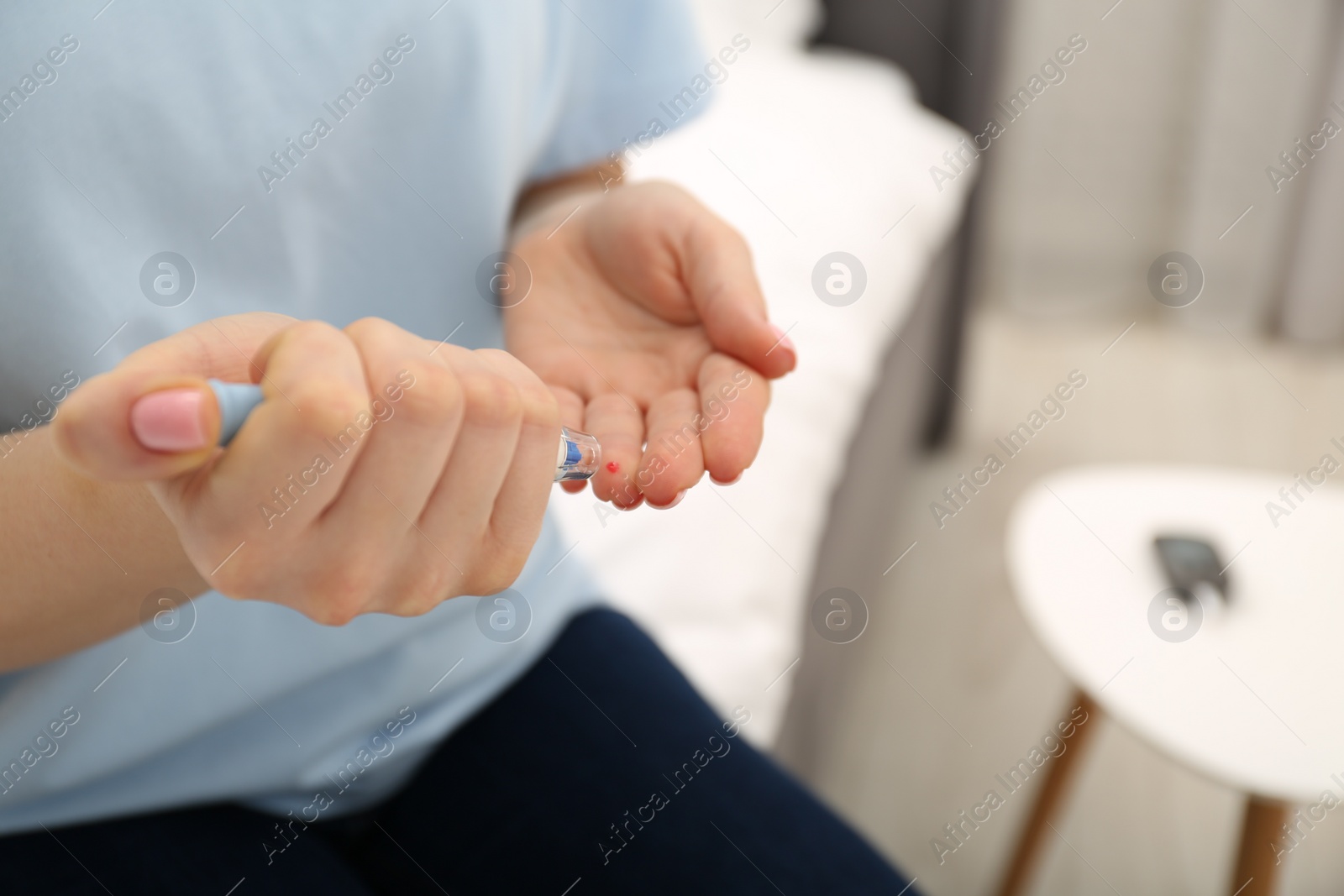 Photo of Diabetes. Glucose testing. Woman using lancet pen at home, closeup