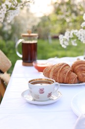 Photo of Stylish table setting with tea and croissants in spring garden