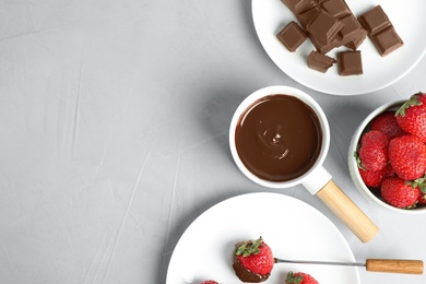 Photo of Flat lay composition with fondue pot and chocolate on grey table. Space for text