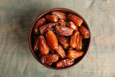 Sweet dried dates in bowl on light blue wooden table, top view