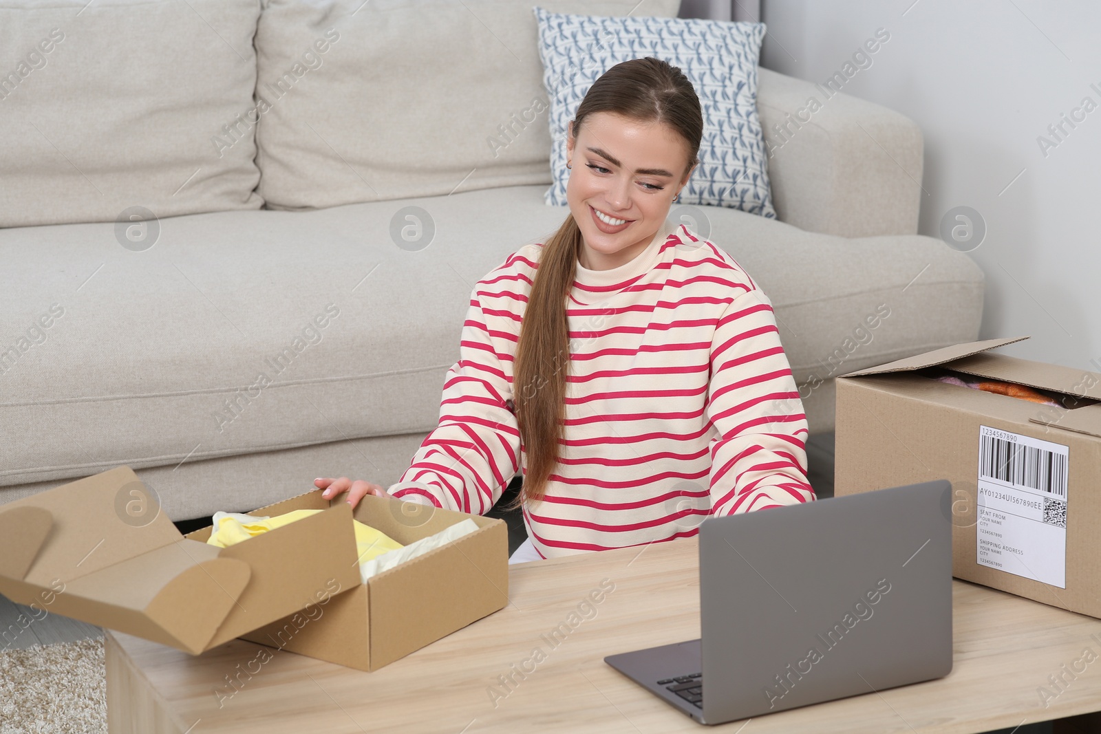 Photo of Happy woman with laptop and parcel at home. Online store