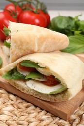 Delicious pita sandwiches with mozzarella, tomatoes and basil on wicker mat