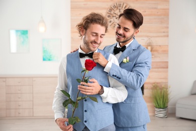 Happy newlywed gay couple with flower at home