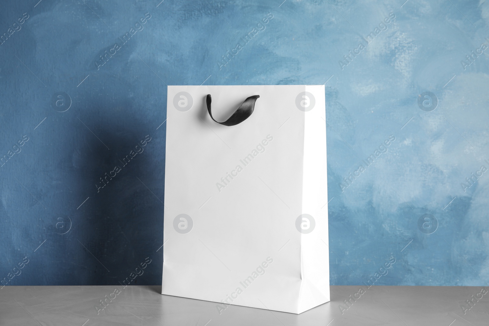 Photo of Paper shopping bag on table against color background. Mock up for design