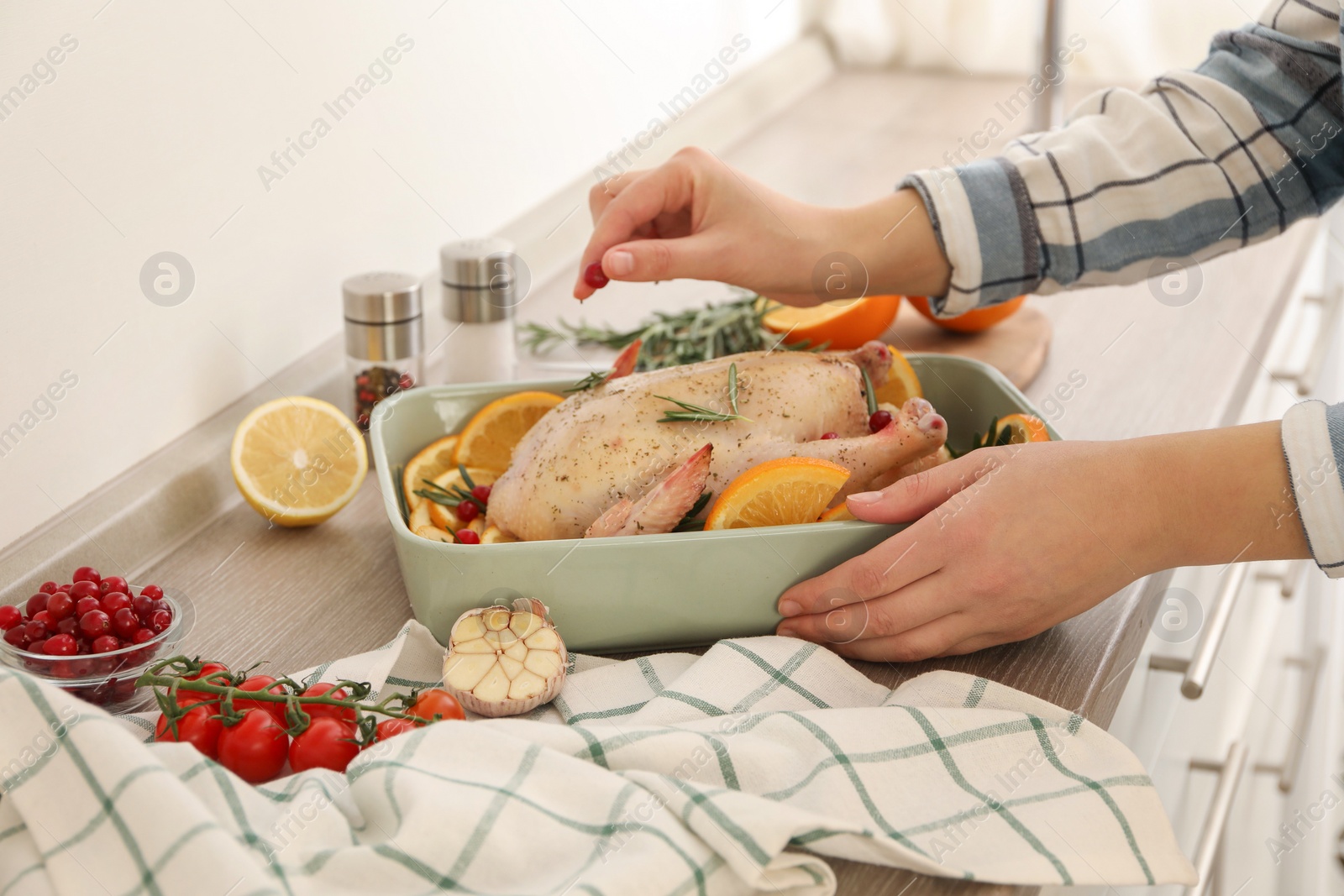 Photo of Woman holding baking pan with Chicken and orange slices at countertop, closeup