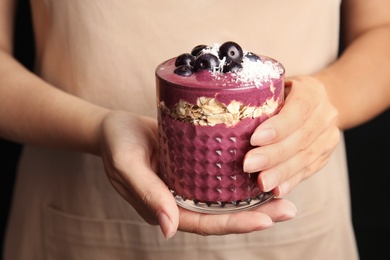 Photo of Woman holding glass with tasty acai smoothie, closeup