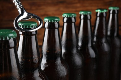 Opening bottle of beer on wooden background, closeup. Space for text