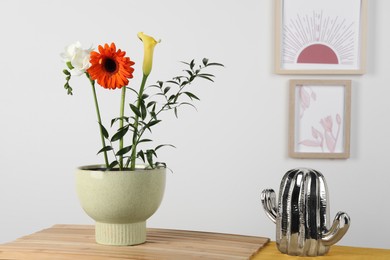 Stylish ikebana as house decor. Beautiful fresh flowers on table near white wall