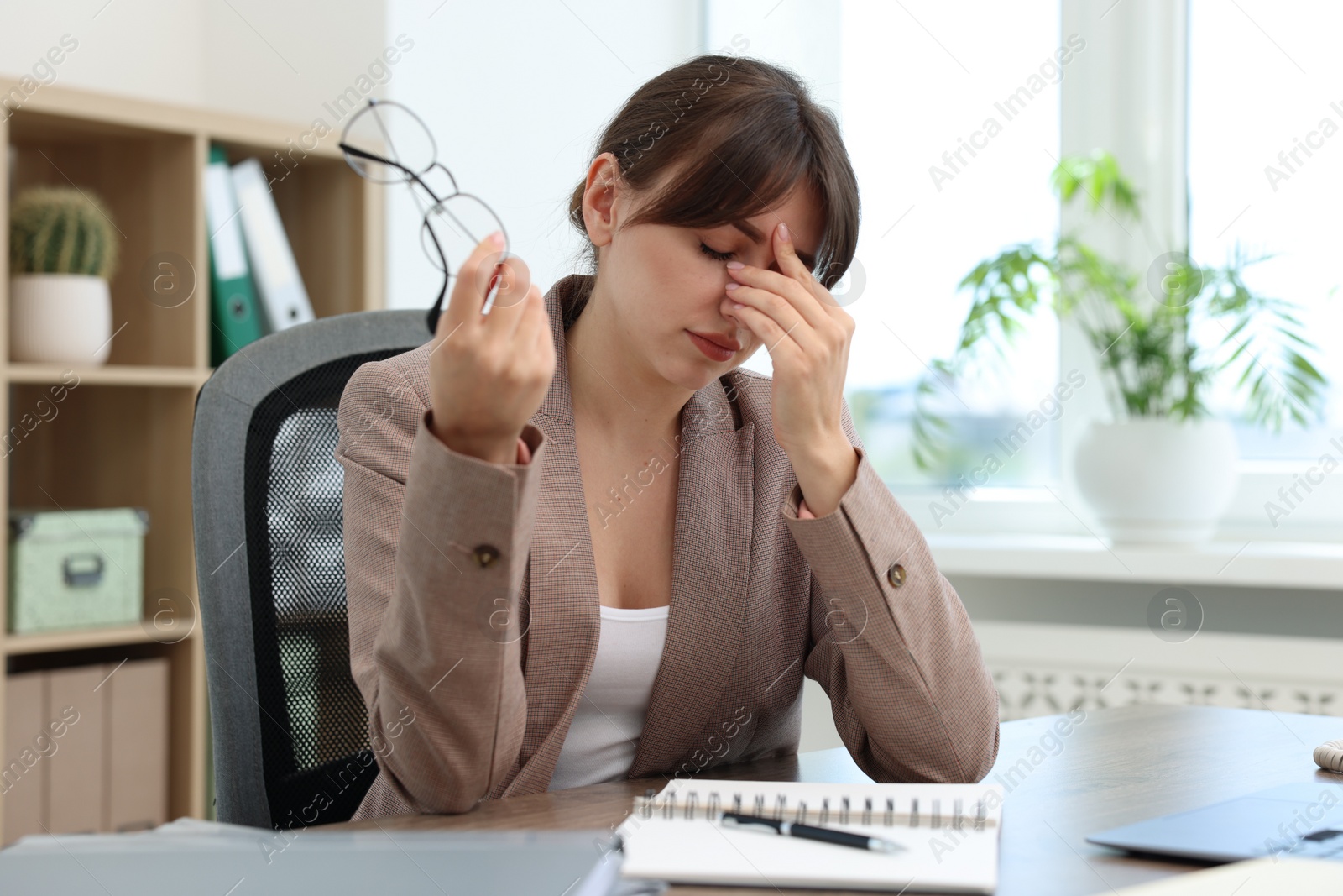 Photo of Overwhelmed woman suffering at table in office