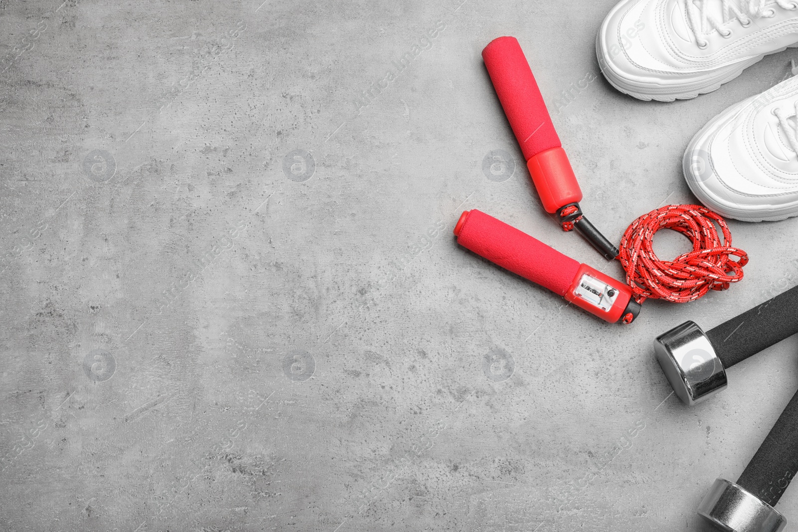 Photo of Flat lay composition with jump rope, gym equipment and space for text on grey background