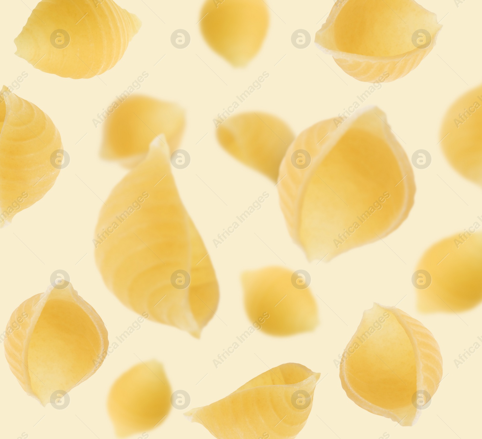 Image of Raw conchiglie pasta flying on beige background