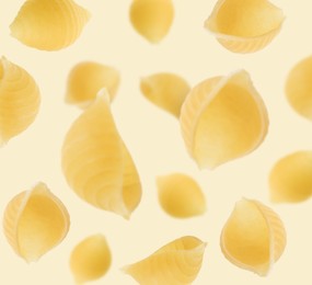 Image of Raw conchiglie pasta flying on beige background