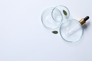 Petri dishes with samples of cosmetic oil, pipette and green leaves on white background, flat lay. Space for text