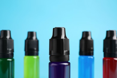 Photo of Bottles with different food coloring on light blue background, closeup