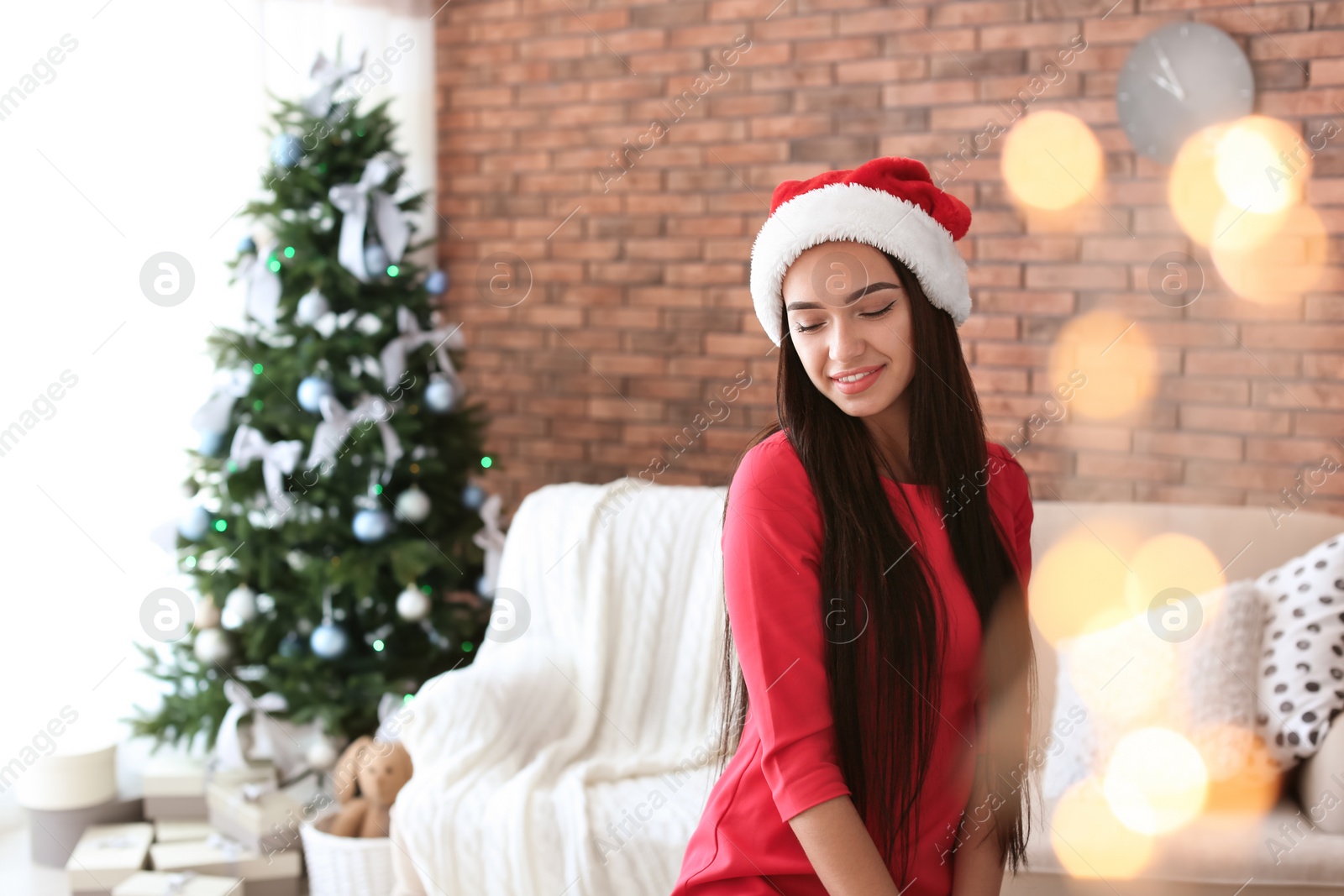 Photo of Beautiful young woman in Santa hat at home. Celebrating Christmas