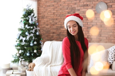 Photo of Beautiful young woman in Santa hat at home. Celebrating Christmas