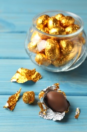 Chocolate eggs wrapped in golden foil on light blue wooden table