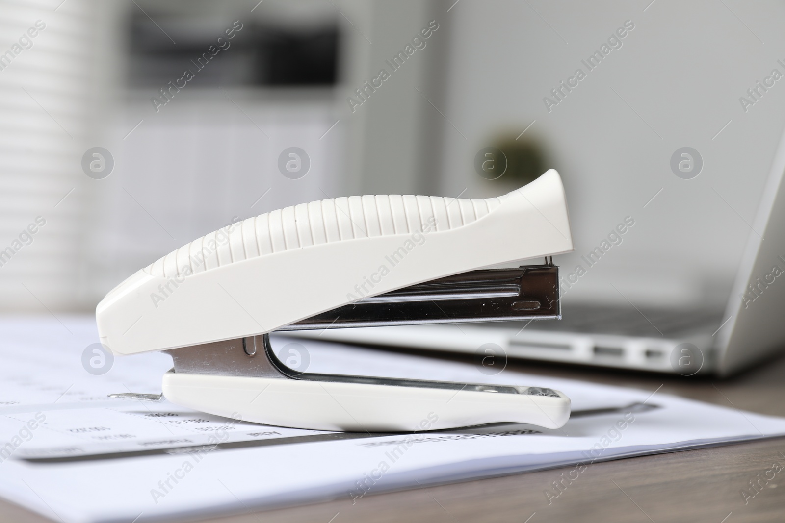 Photo of Stapler and document on table indoors, closeup