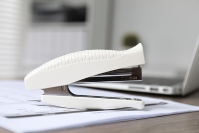 Stapler and document on table indoors, closeup