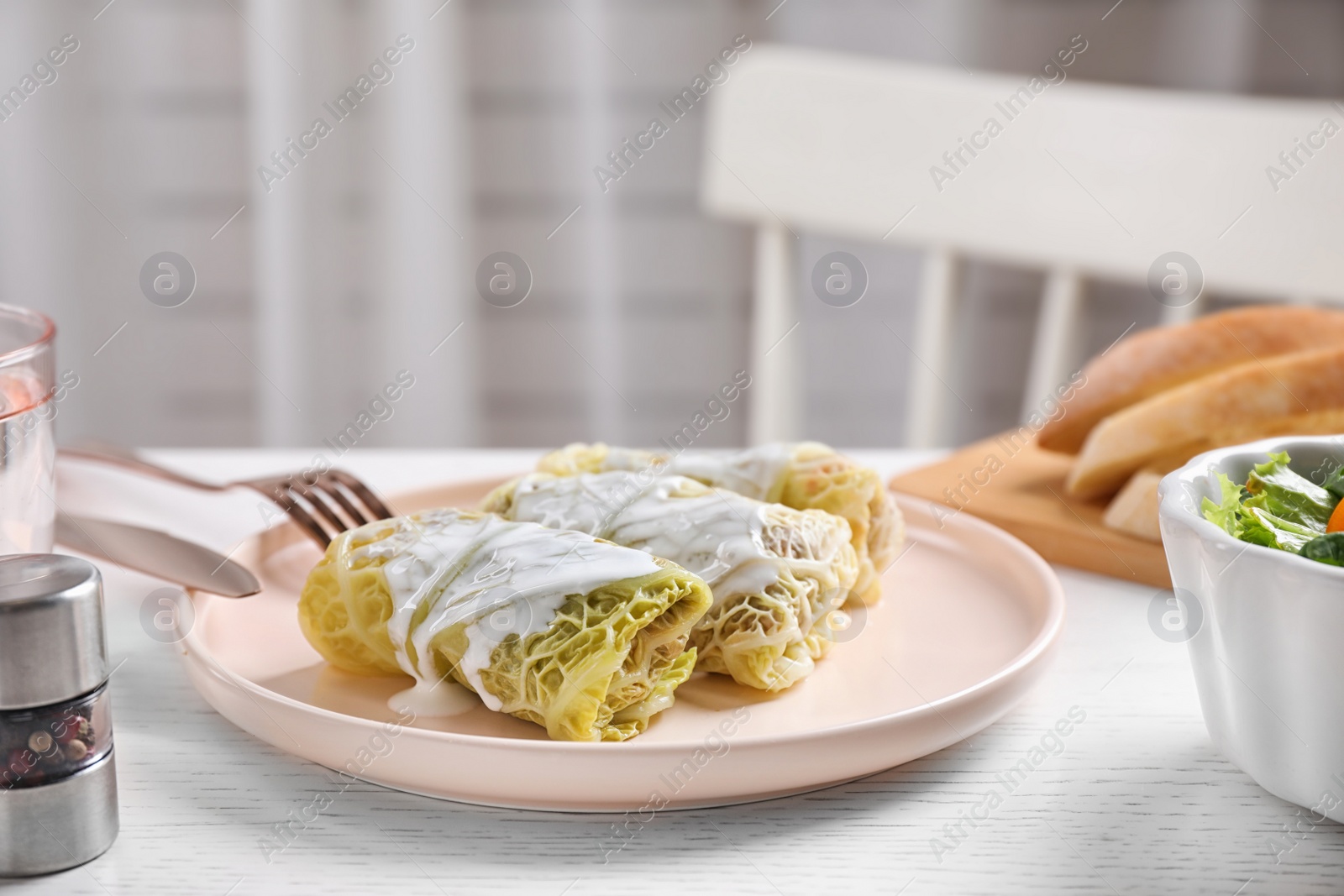 Photo of Delicious cabbage rolls served on white wooden table indoors. Space for text