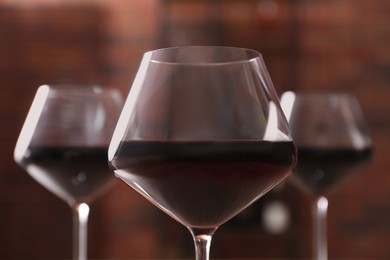 Photo of Tasty red wine in glass against blurred background, closeup