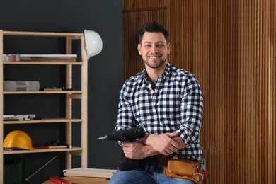 Photo of Handsome working man with electric screwdriver indoors. Home repair