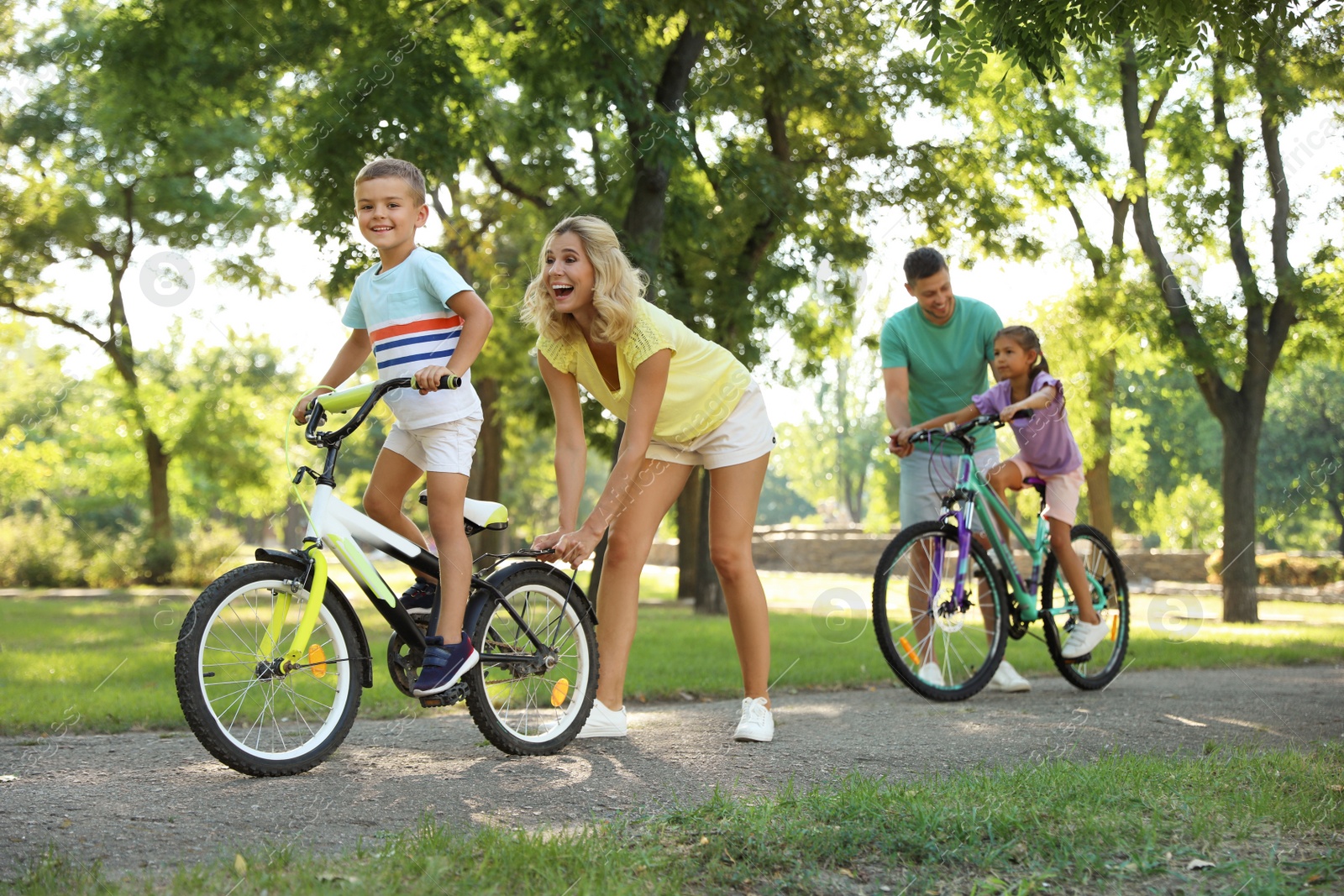 Photo of Happy parents teaching their children to ride bicycle in park