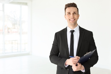 Photo of Male real estate agent with clipboard indoors