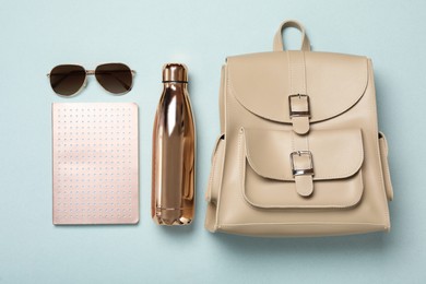 Photo of Stylish urban backpack with different items on light background, flat lay