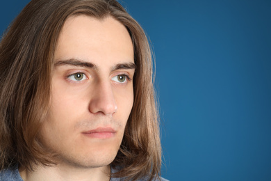Portrait of young man on blue background, closeup