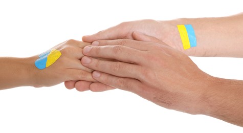 Photo of Man and woman with painted Ukrainian flags on their hands against white background, closeup