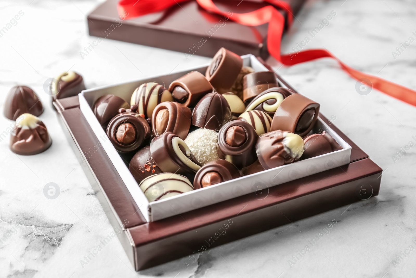 Photo of Box with different tasty chocolate candies on table