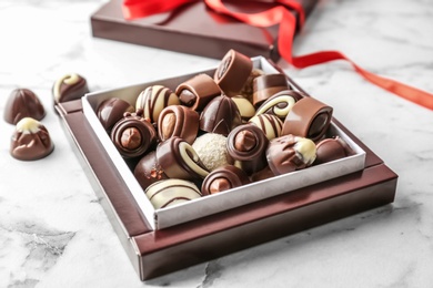 Box with different tasty chocolate candies on table