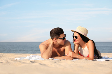 Photo of Happy couple resting on sunny beach. Space for text