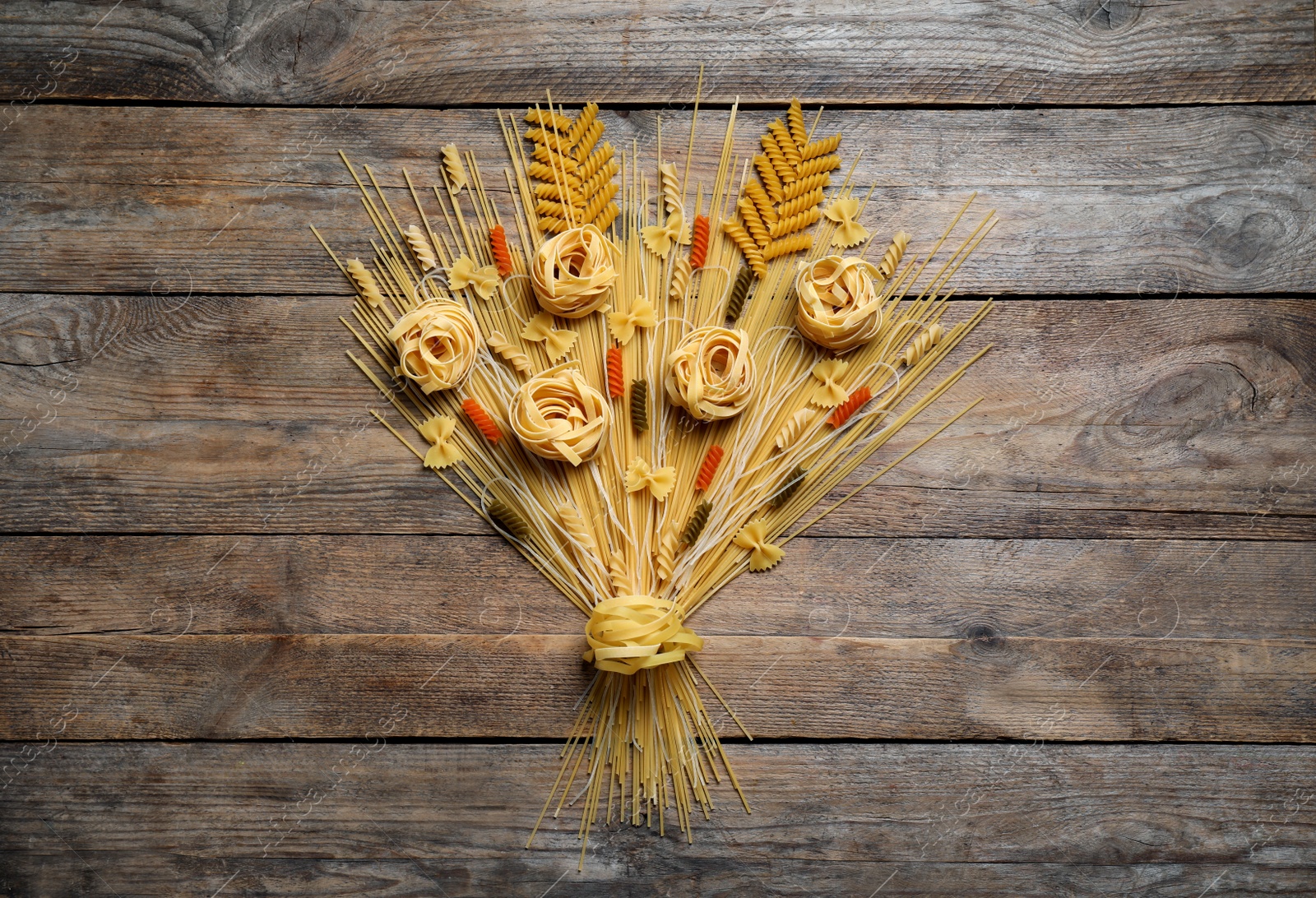 Photo of Bouquet made with different types of pasta on wooden table, top view