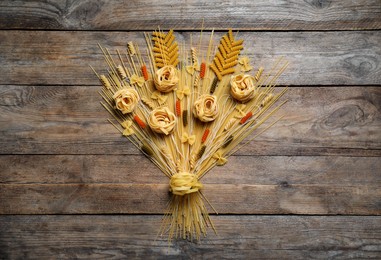 Photo of Bouquet made with different types of pasta on wooden table, top view