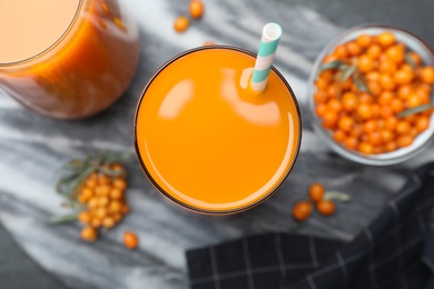 Photo of Delicious sea buckthorn juice with straw on board, top view