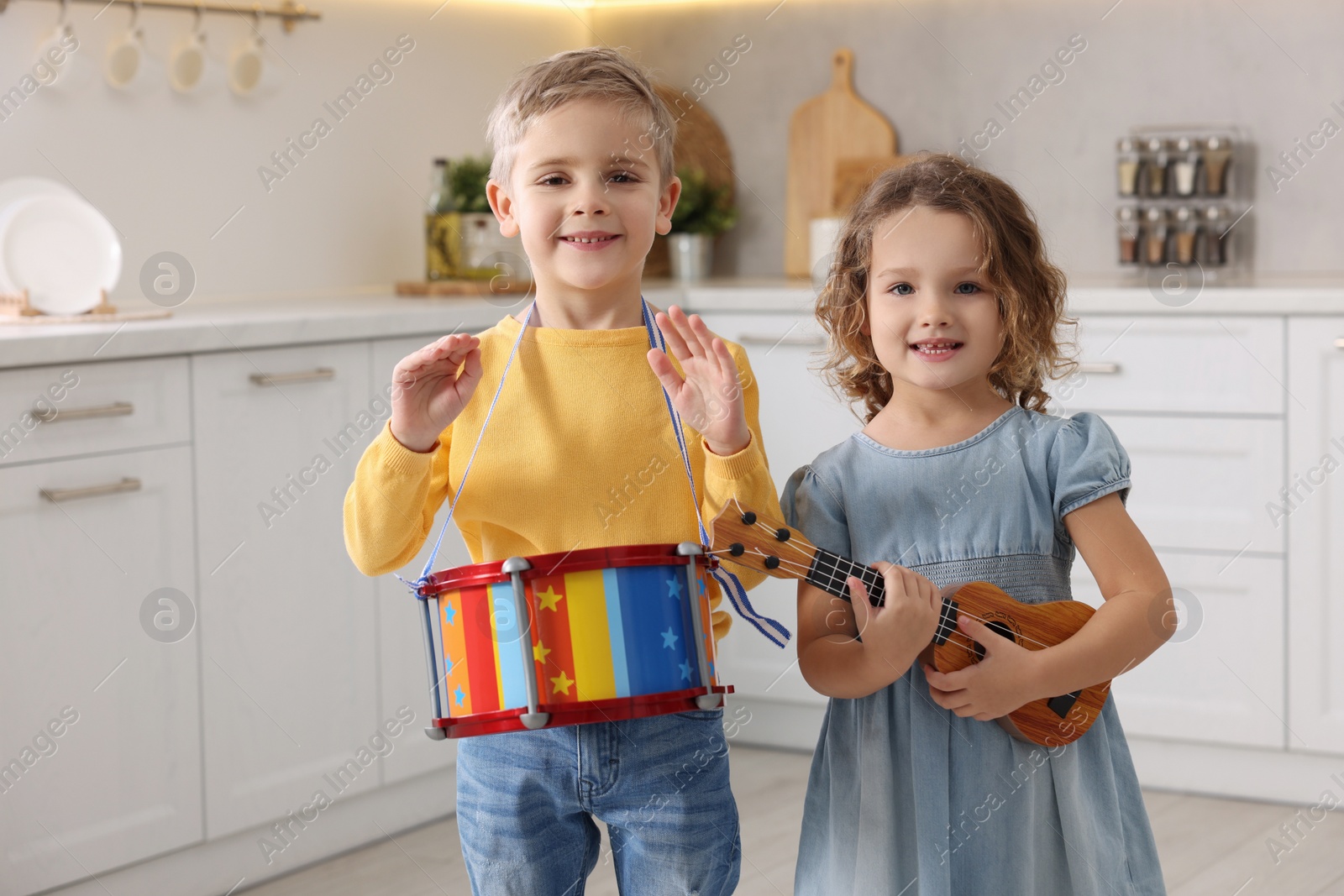 Photo of Little children playing toy musical instruments in kitchen